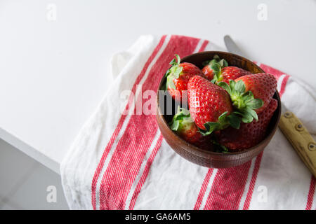 Erdbeeren in Holzschale auf Geschirrtuch, roten und weißen Streifen auf dem Küchentisch Stockfoto