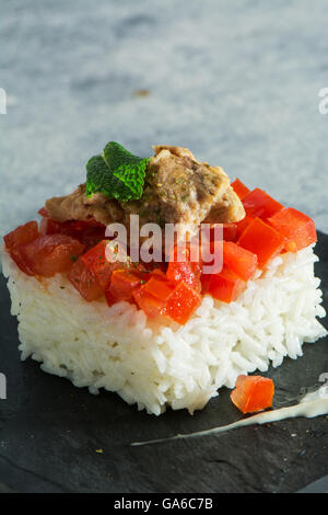 weißer Reis mit Tomaten und Thunfisch auf Platte schwarz Fliese Stockfoto