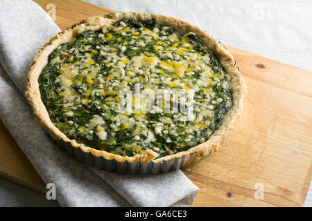 Spinat-Quiche und Gemüse mit Käse überbacken auf Holzbrett Stockfoto