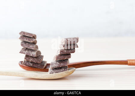 Kochen Schokolade Stücke übereinander auf Holzlöffel mit weißen textfreiraum ausgeglichen Stockfoto