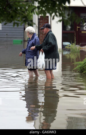 Zwei Menschen waten durch eine Straße im überfluteten Tewkesbury, Gloucestershire. Stockfoto