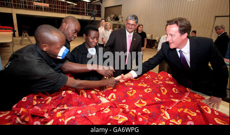 David Cameron, Vorsitzender der britischen Konservativen Partei (rechts), trifft sich während eines zweitägigen Besuchs im Land mit Mitarbeitern der Textilfabrik Utexrwa in Kigali, Ruanda. Stockfoto