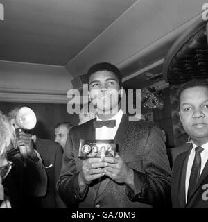 Weltmeister Muhammad Ali (Cassius Clay) mit vier Goldmedaillen, Nachbildungen der Churchill-Medaillen, überreicht von einem Bewunderer, Oberst Hubert Julian von Ecuador, der sie extra überfliegen ließ. Ali empfing sie auf einer Pressekonferenz im Isows Restaurant in Soho, wo er sich bei allen dafür bedankte, dass sie ihn so nett behandelt haben. Stockfoto