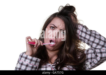 Studioaufnahme von einem verschlafenen aussehendes Modell tragen ihre Pyjamas und eine Zahnbürste hautnah.  Isoalted auf weißem Hintergrund. Stockfoto