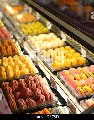 Französische Macarons in leuchtenden Farben locken die Naschkatze Shopper Gourmet-Stil in den Reihen der Anzeige in einem Kühler im Gebäck sh Stockfoto