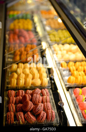 Französische Macarons in leuchtenden Farben locken die Naschkatze Shopper Gourmet-Stil in den Reihen der Anzeige in einem Kühler im Gebäck sh Stockfoto