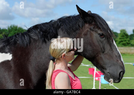 Junges Mädchen streicheln ein schwarzen und weißes Pferd in einem paddock Stockfoto