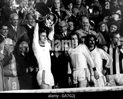 (L-R) Bayern München Kapitän Franz Beckenbauer hebt nach dem Sieg seines Teams im Jahr 4-0 den EM-Cup an, während die Teamkollegen Johnny Hansen und Gerd Muller die Reaktion der Bayern-Fans beobachten Stockfoto