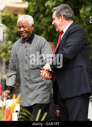 Der britische Premierminister Gordon Brown hilft dem ehemaligen südafrikanischen Präsidenten Nelson Mandela auf dem Podium, als heute auf dem Parliament Square in London eine Statue zu Mandelas Ehren enthüllt wird. Stockfoto