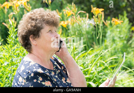lockige Frau mit Handy und Tablet außerhalb Stockfoto