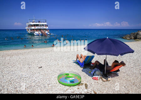 Touristen genießen Sie einen Sommerabend am Strand von Xigia als ein Boot mit anderen Touristen Ansätze in Zakynthos am 25. Juli 2015. Stockfoto