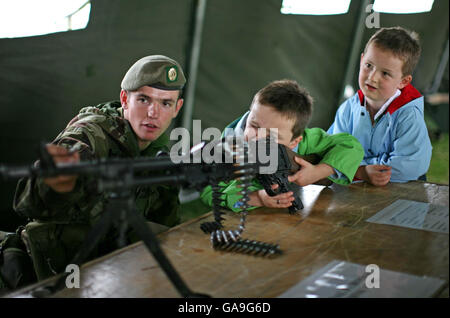Reese Thompson, 4 Jahre alt, aus Rathmolyon, County Meath, mit seinem Bruder Jordan im Alter von 6 Jahren (rechts), wird von CPL Daithij Mac Eamoinn aus dem 62. Infanterie-Reserve-Bataillon im Rekrutierungszelt der irischen Streitkräfte der irischen Armee auf der Bray Air Display, Bray, County Wicklow, ein Mehrzweck-Maschinengewehr gezeigt. Stockfoto