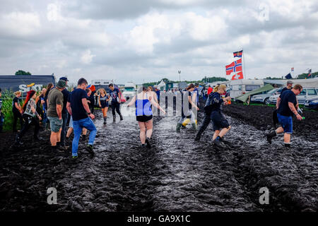 Wacken, Deutschland. 4. August 2016. Metal-Fans geht durch den Schlamm auf dem Gelände das Wacken Open Air Festival in Wacken, Deutschland, 4. August 2016. Das Gelände von der laut den Organisatoren ist größte Metal-Festival nach starken Regenfällen im Schlamm bedeckt. Foto: AXEL HEIMKEN/Dpa/Alamy Live News Stockfoto