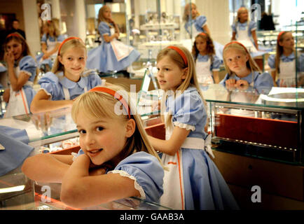 Eine Gruppe von Mädchen, die als Alice im Wunderland gekleidet sind, schaut sich den neuen Wonder Room of Jewelry, Uhren und Luxusgeschenke im Londoner Kaufhaus Selfridges an. Stockfoto