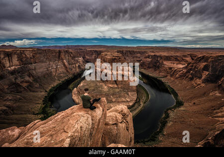 Horseshoe Bend, Colorado River und ein Wanderer am Rand sitzen und genießen Sie den Panoramablick. Stockfoto