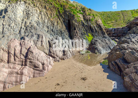 Die vertikalen Gesteinsschichten und Mann gemacht Küstenschutzes Erosion in den Klippen am Bigbury am Meer, South Devon, England, UK Stockfoto