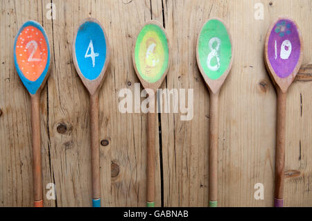 Bunten Holzlöffel mit Zahlen in einer Sequenz in einer Reihe auf einem Holztisch angeordnet Stockfoto