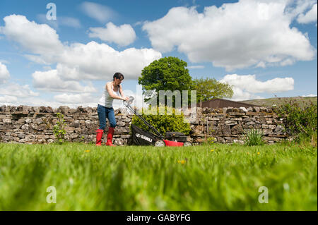 Lady Mähen Wiese im Garten mit Benzin betriebene Rasenmäher. Hawes, North Yorkshire, UK. Stockfoto