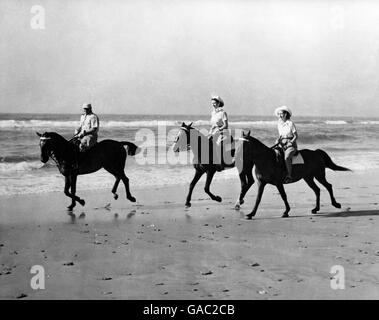 Die Prinzessinnen genossen eine Auszeit von der königlichen Tour durch Südafrika, als sie auf dem goldenen Sand von Bonza Beach, East London, reiten, Prinzessin Elizabeth (Mitte) reitet auf Yvonne Hayhoes 'Jill', während Prinzessin Margaret auf dem 'Treasure' von Pat O'Reilly aus East London reitet, Wer wird gesehen, wie er die Prinzessinnen eskortiert. Stockfoto