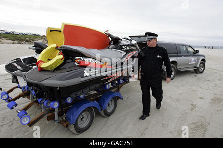 Der örtliche Polizist Danny Lapsley von der Polizei Strathclyde, der der einzige Beamte auf der Insel Tiree ist, blickt auf einige Jetskis, während er auf seinem Schlag am Strand von Balevullin auf der Insel Tiree ist. Stockfoto