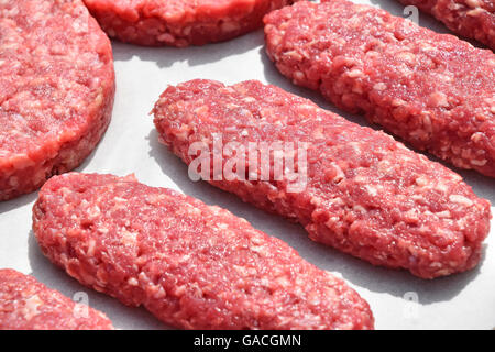 Rohes, rotes Fleisch-Burger, Kebab oder Patty Schnitzel von gehacktem Rindfleisch, Lamm, Schwein auf weißes Pergamentpapier bereit für das Kochen Stockfoto