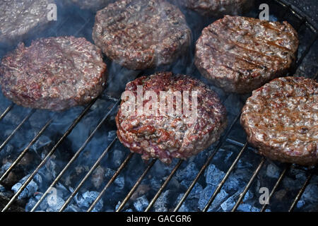 Rind oder Schwein Fleisch Grill Burger für Hamburger vorbereitet hautnah auf Rauch Barbeque-Grill, gegrillt Stockfoto