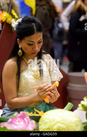 beim fair Festival des Ostens in Bologna, eine Thai-Frau eine Karotte als Lebensmittel Dekoration schnitzen Stockfoto