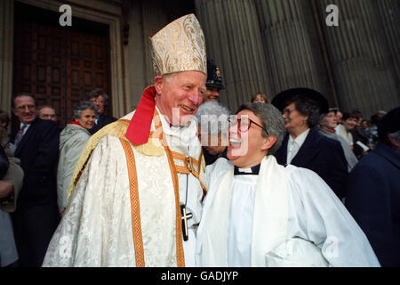 Ein jubelender, neu ordinierter Priester teilt einen Witz mit dem stellvertretenden Bischof von London vor der St. Paul's Cathedral in London. Stockfoto