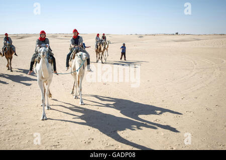 Beduinen führt Touristen auf Kamelen auf kurze touristische Tour rund um den Beginn der Sahara Wüste in Douz, Tunesien. Stockfoto