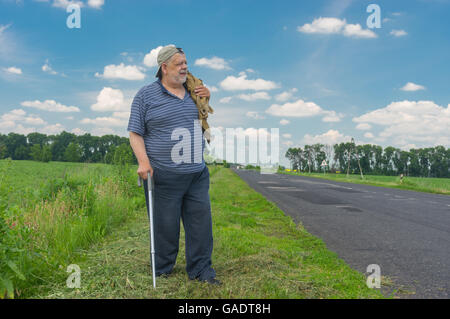 Senior woman Walking Stick steht auf einem Straßenrand Stockfoto