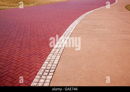 Muster und Texturen auf Promenade mit Rasen Kanten und weiße Mittellinie oben Blick auf Beton und rot gepflastert Stockfoto