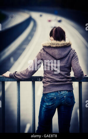 Frau steht an der Reling von einer Autobahnbrücke Stockfoto