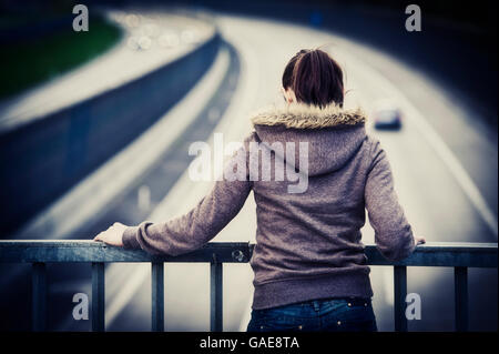 Frau steht an der Reling von einer Autobahnbrücke Stockfoto