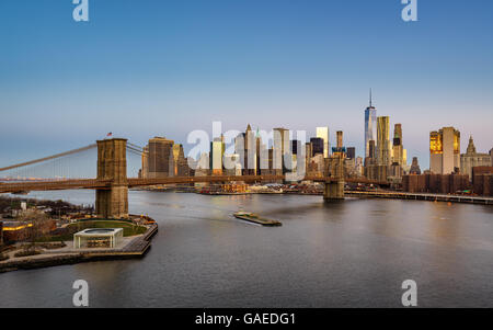 Blick auf die Brooklyn Bridge bei Sonnenaufgang mit Manhattan Financial District Wolkenkratzern und dem East River. New York City Stockfoto