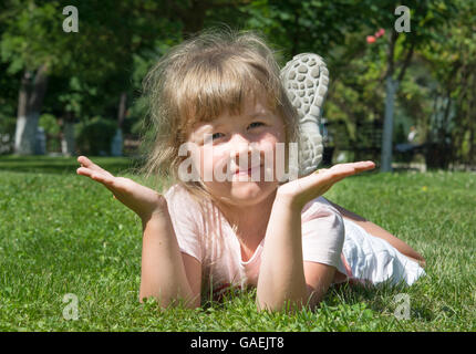 fröhliche kleine Mädchen auf der Wiese liegend Stockfoto