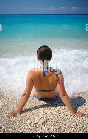 Frau im Bikini am Strand, mit Blick auf das Meer von Wellen getroffen Stockfoto