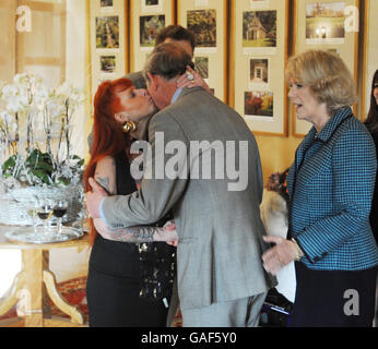 Der Prinz von Wales bekommt einen Kuss von Linda Taylor, die während ihres Besuchs im Highgrove-Haus mit einer Tätowierung bedeckt wurde, während die Herzogin von Cornwall in Tetbury, Gloucestershire, zuschaut. Stockfoto