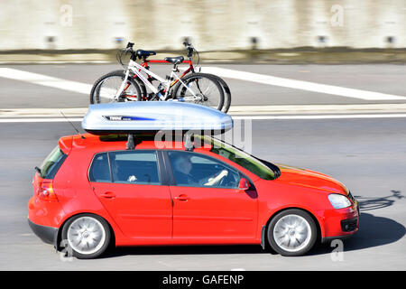 Rote Auto & Fahrer fahren UK Autobahn mit Box und Fahrrad Dachträger geladen mit Herren und Damen Fahrrad für den Radsport Pause Stockfoto