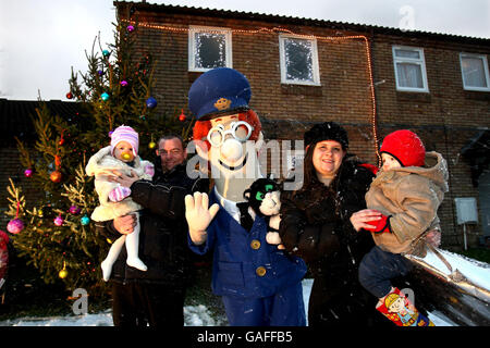 Mel Spears hält Caitlin, 1 und Gewinner des Wettbewerbs, Julie Quarterman und Kieran, 2, stehen mit Postman Pat, außerhalb der eigenen Wohnung in Aylesbury, nachdem Julie gewann einen Wettbewerb um das Haus in eine magische Weihnachts-Szene verwandelt haben. Tausende von funkelnden Lichterketten, weiß Abplatzungen Schnee, den am besten gekleideten Baum auf der Straße und von ihrer ganz eigenen Sternsinger begleitet. Bild Datum Montag, 17. Dezember 2007. Bildnachweis sollte Chris Radburn/PA Wire lesen. Stockfoto