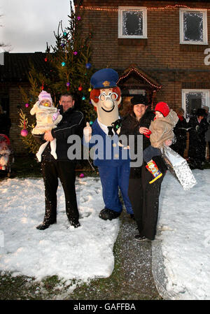 Mel Spears hält Caitlin, 1 und Gewinner des Wettbewerbs, Julie Quarterman und Kieran, 2, stehen mit Postman Pat, außerhalb der eigenen Wohnung in Aylesbury, nachdem Julie gewann einen Wettbewerb um das Haus in eine magische Weihnachts-Szene verwandelt haben. Tausende von funkelnden Lichterketten, Abplatzungen weißem Schnee, der am besten gekleideten Baum in der Straße und bei ihren ganz eigenen Sternsinger. Bild Datum Montag, 17. Dezember 2007. Bildnachweis sollte Chris Radburn/PA Wire lesen. Stockfoto