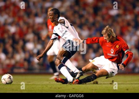 Fußball - FA Barclaycard Premiership - Manchester United / Bolton Wanderers. Ricardo Gardner von Bolton Wanderers kämpft mit David Beckham von Manchester United um den Ball Stockfoto