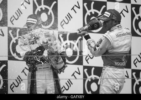 (L zu R): Zweiter Platz Heikki Kovalainen (FIN) Renault und Rennsieger Lewis Hamilton (GBR) McLaren Mercedes feiern mit Champagner auf dem Podium Formel-1-Weltmeisterschaft, Rd15, japanischer Grand Prix, Race Day, Fuji Speedway, Fuji, Japan Stockfoto