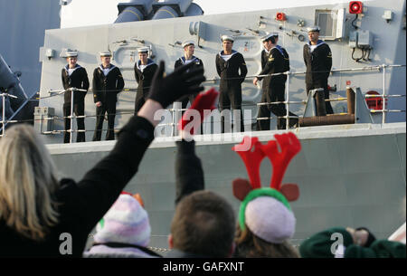 Familienmitglieder winken an Bord der Royal Navy Fregatte HMS Richmond zu ihren Lieben, als sie heute nach einer ereignisreichen siebenmonatigen Sicherheitsmission im Arabischen Golf zu Weihnachten nach Portsmouth zurückkehrt. Stockfoto