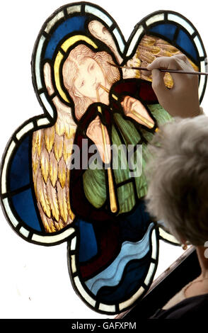 Susan Matthews, Kuratorin des Buntglasmuseums in Ely Cathedral, Ely, Cambridgeshire, hält ein Cinquefoil-Buntfenster mit einem Minstrel Angel von William Morris. Stockfoto