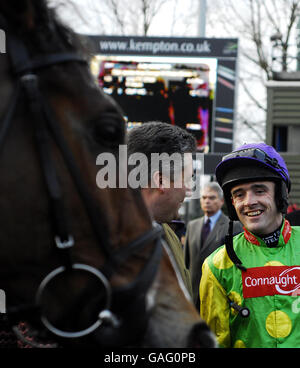 Kauto Star sieht zu, wie Trainer Paul Nicholls mit Jockey Ruby Walsh nach dem Sieg in der Stan James King Georg VI Chase auf Kempton Park Racecourse spricht. Stockfoto