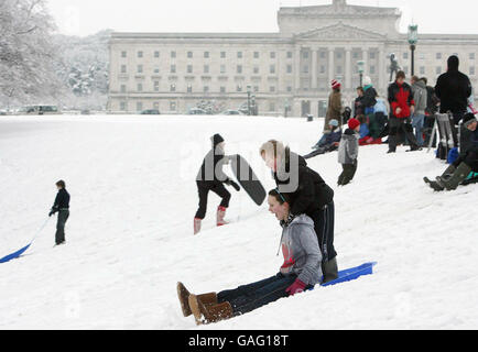 Familien, die den Schnee im Stormont-Anwesen in Belfast genießen. Stockfoto