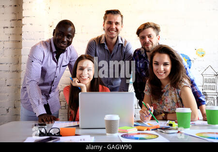 Porträt der glückliche junge Menschen in einer Besprechung Blick in die Kamera und lächelnd. Junge Designer arbeiten gemeinsam an einem kreativen Projekt. Stockfoto
