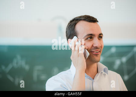 Porträt-Closeup auf einen Mann sprechen Telefon im Klassenzimmer vor der Tafel Stockfoto