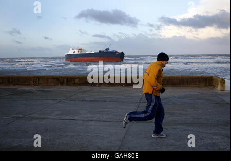 Ein Jogger läuft am Frachtschiff Riverdance vorbei, das aufgrund der starken Winde in Blackpool auf Grund gelaufen ist. Stockfoto