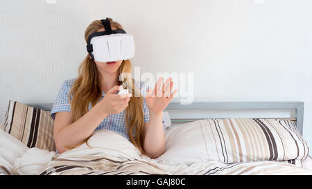 Schöne Frau mit VR Kopfhörer im Bett Stockfoto